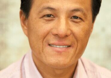 Portrait of a middle-aged man smiling warmly at the camera.