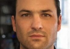 Portrait of a serious man with dark hair and a focused expression.