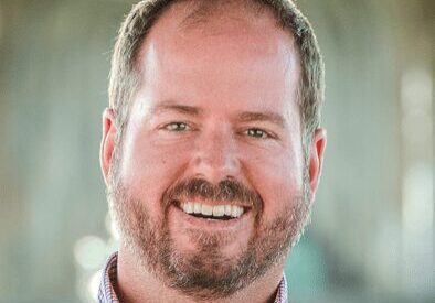 Smiling man with a beard in a casual shirt.