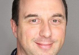 A man with a friendly smile and short dark hair.