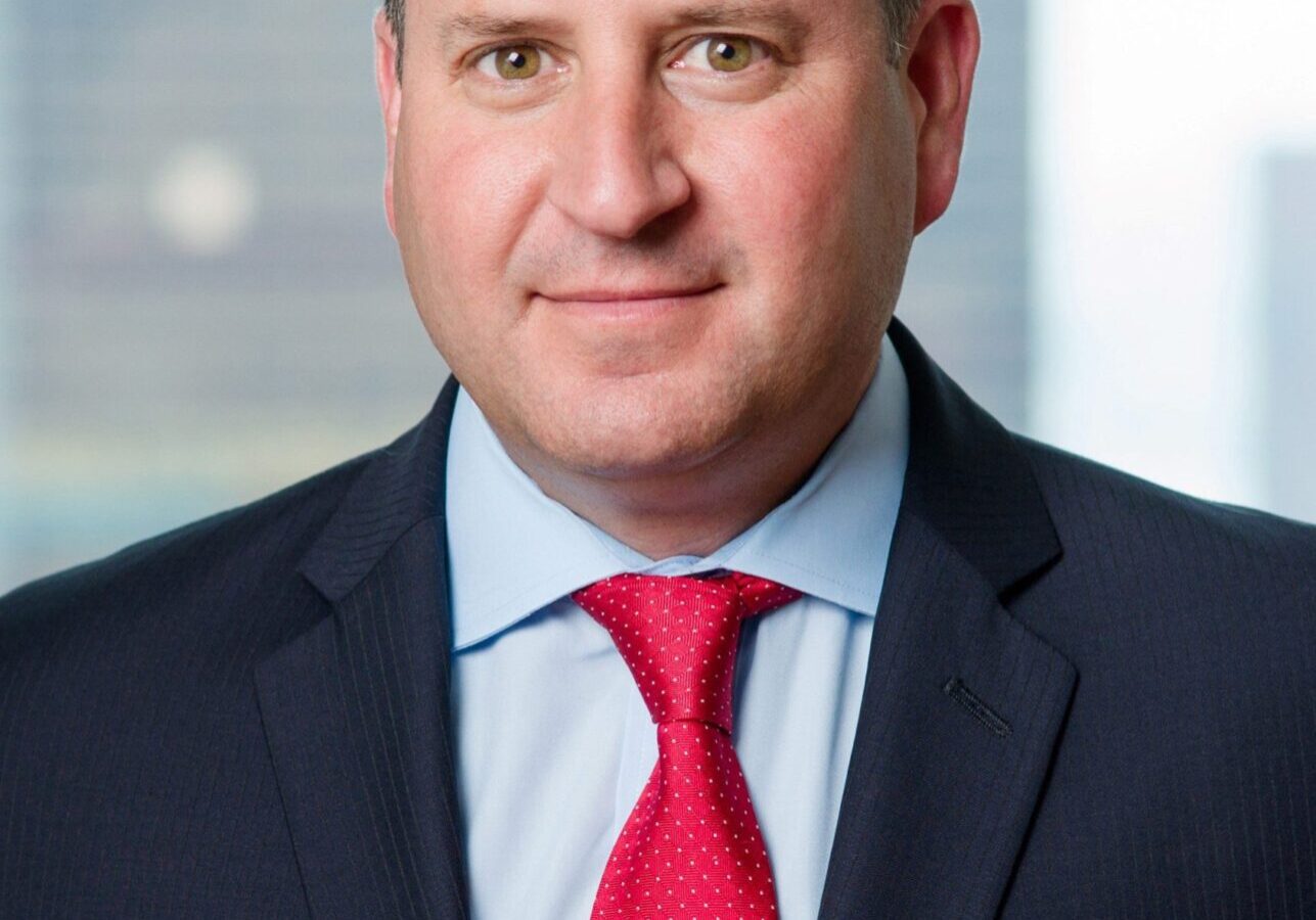 Professional man in a suit with a red tie against a blurred office background.