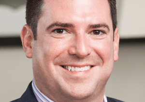 Smiling man in a suit and striped shirt.