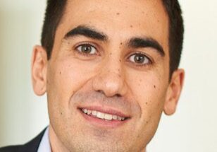 Portrait of a smiling man in a suit jacket and white shirt.