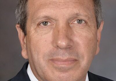 Professional headshot of a middle-aged man in a suit.