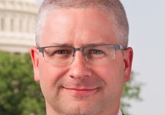 Professional man with glasses standing outdoors near a government building.