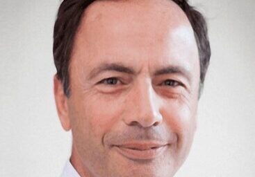 Portrait of a middle-aged man with a slight smile in a white shirt.