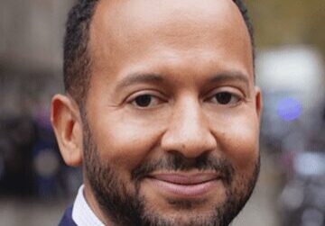 Portrait of a smiling man in a suit outdoors.