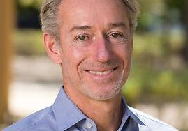 Smiling man in a light blue shirt outdoors.
