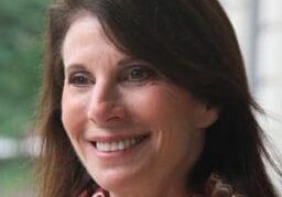 Smiling woman with dark hair wearing a patterned scarf.