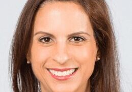 Professional headshot of a smiling woman with brown hair.
