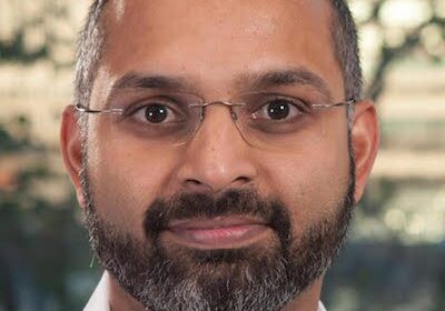 Portrait of a man with glasses and a beard smiling gently.