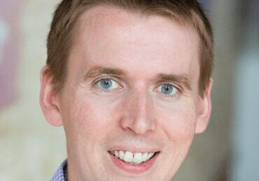 Portrait of a smiling man with short hair and blue eyes.
