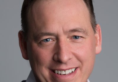 Smiling middle-aged man with short hair in a dark sweater.