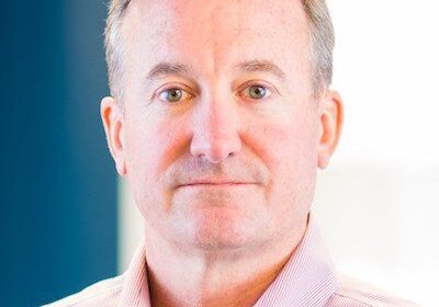 Portrait of a middle-aged man in a light pink shirt.