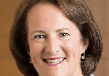 Smiling woman with brown hair and pearl earrings.