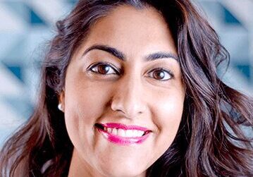 Smiling woman with long dark hair and bright lipstick.