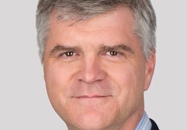 Portrait of a middle-aged man with gray hair in business attire.
