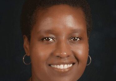 Portrait of a smiling woman with short hair and hoop earrings.