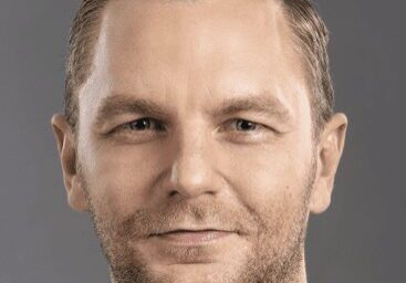 Portrait of a confident man with short hair and a subtle smile.