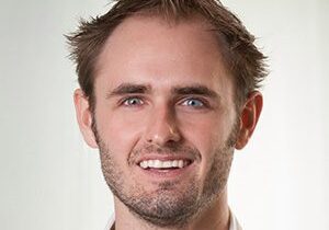 Portrait of a smiling man with short hair and a light beard.
