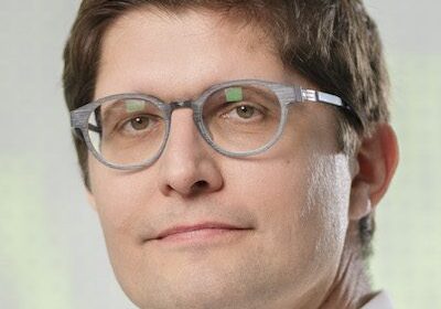 Man with glasses looking thoughtfully at the camera.