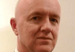 Portrait of a middle-aged bald man in formal attire.