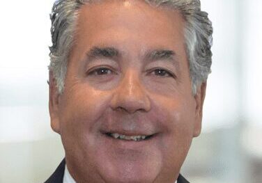 Smiling middle-aged man in a suit with gray hair.