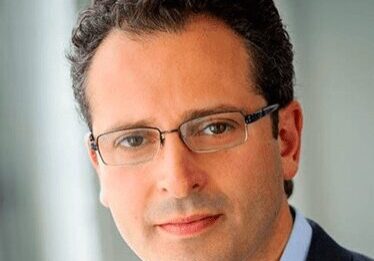 Portrait of a man with glasses in a suit.