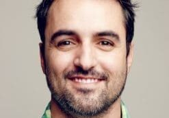 Smiling man with a beard and green plaid shirt.