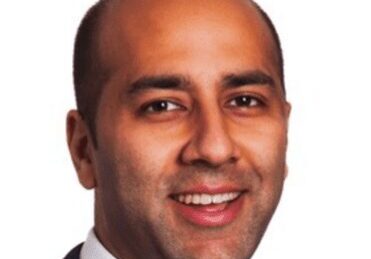Professional headshot of a smiling man in a suit.