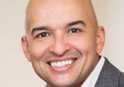 Smiling bald man in a gray blazer.