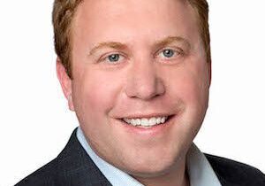 Professional headshot of a smiling man in a suit.