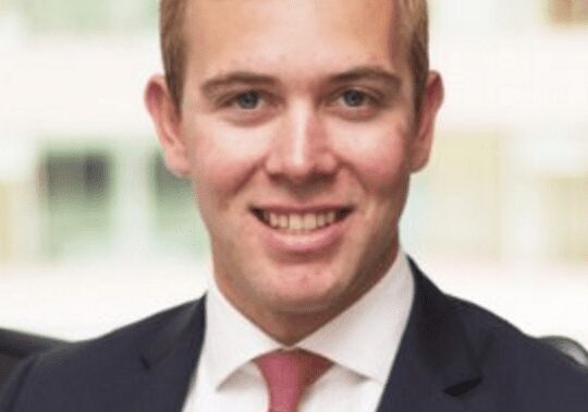 A young man in a suit and tie smiling at the camera.