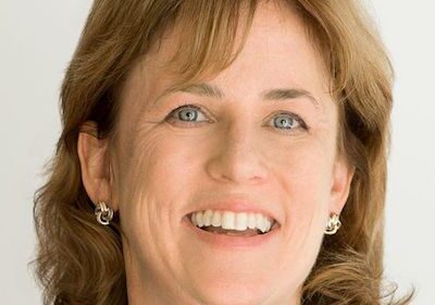 Smiling woman with short brown hair and hoop earrings.