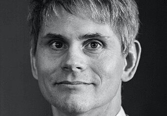 Black and white portrait of a man with light hair and a slight smile.
