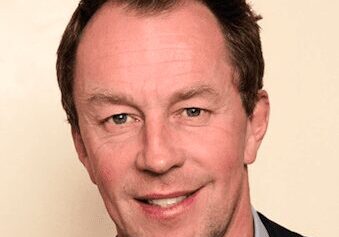 Portrait of a smiling middle-aged man in a suit jacket.