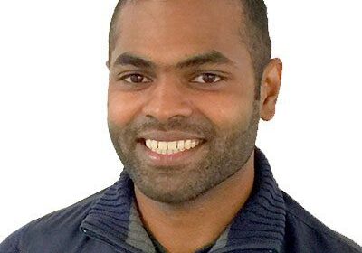 Smiling man in a dark jacket against a white background.