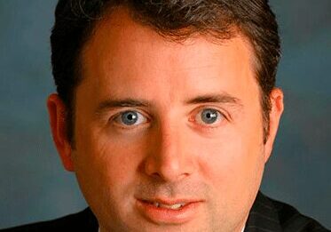 Professional headshot of a man with blue eyes and brown hair.