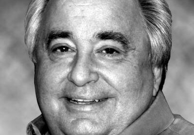 Black and white portrait of an elderly man smiling.