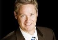 Professional man in a suit smiling against a black background.