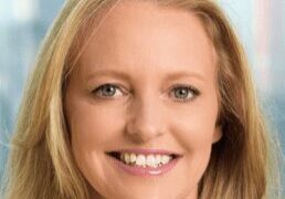 A smiling woman with blonde hair in a professional setting.