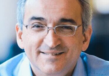 Smiling middle-aged man wearing glasses and a blue shirt.